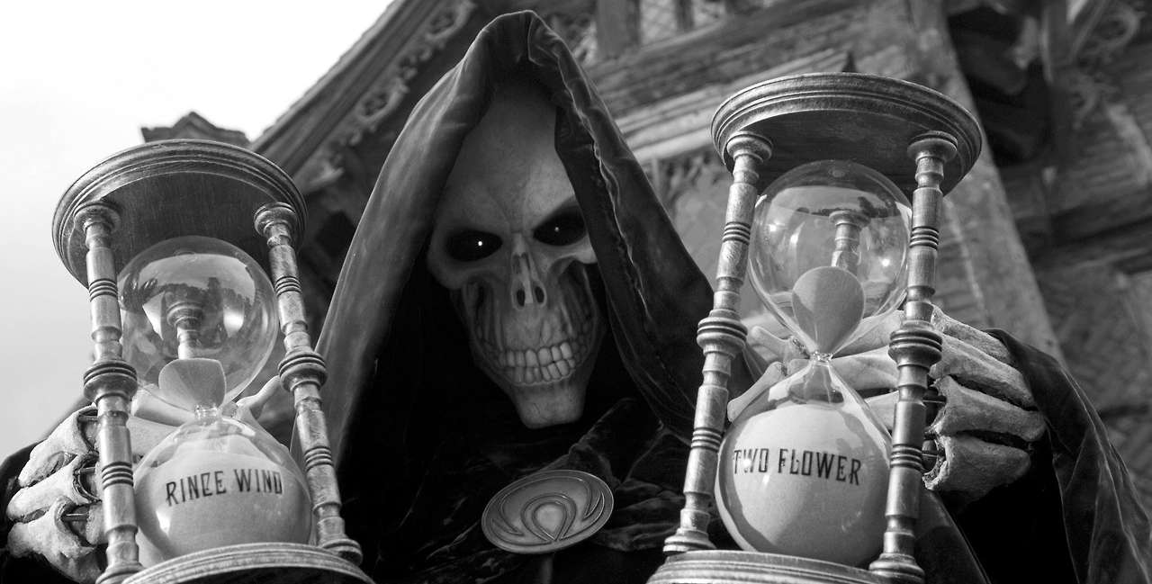 Grim Reaper from the screen adaptation of The Colour of Magic, holding two hourglasses labelled 
